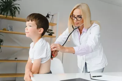 عکس پزشک اطفال در حال معاینه قلب و ریه های یک پسر بچه کوچک