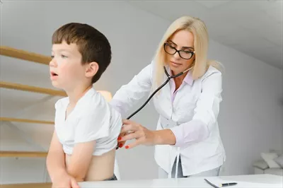 عکس پزشک اطفال در حال معاینه قلب و ریه های یک پسر بچه کوچک