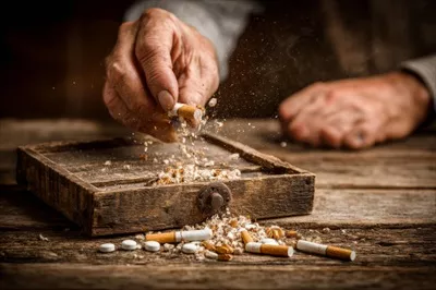 عکس مردی در حال ریختن سیگارها به داخل یک جعبه است