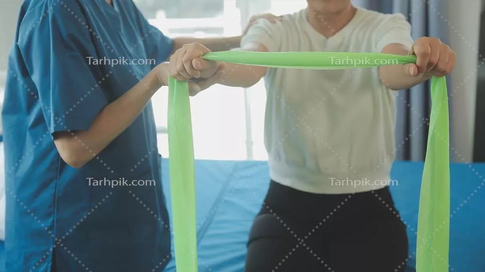 عکس زنی مسن و شاد در حال انجام تمرینات ورزشی در خانه با کمک مربی شخصی