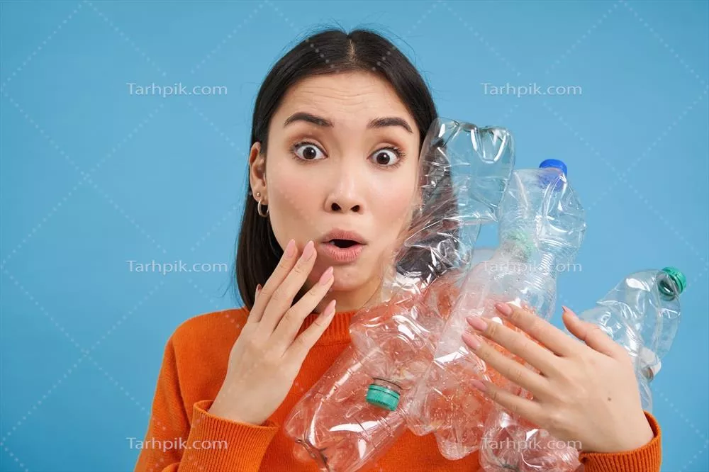 عکس زن کره ای شگفت زده با بطری های پلاستیکی در پس زمینه آبی
