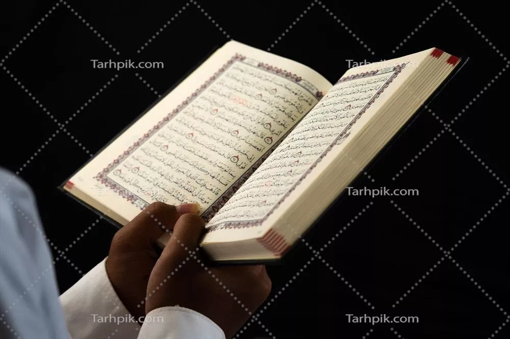 عکس مردی در حال مطالعه قرآن با دقت و تمرکز در یک محیط آرام