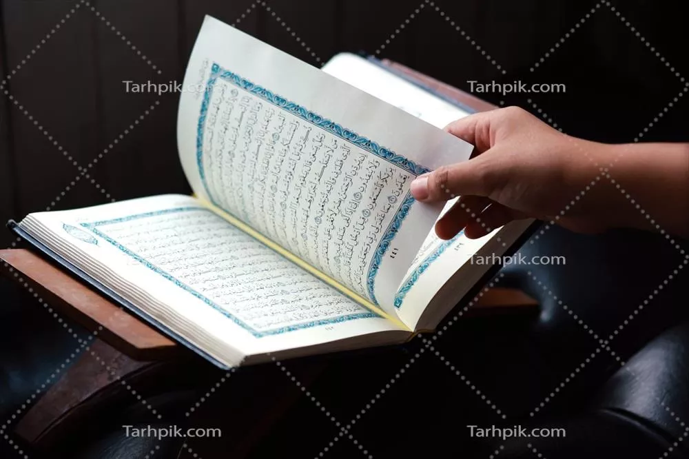 عکس تصویری نزدیک از دست که صفحه ای جدید از قرآن را ورق می زند