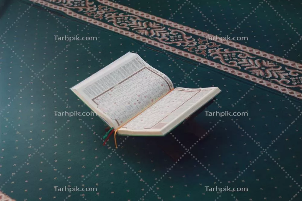 عکس تصویری نزدیک از قرآن کریم بر روی سجاده سبز رنگ با مفهوم اسلامی