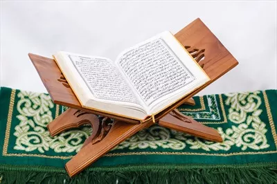 عکس کتاب مقدس قرآن و سجاده نماز بر روی پس زمینه سفید