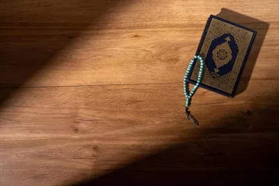 عکس مفهوم اسلامی: قرآن کریم با خط عربی و تسبیح در کنار آن