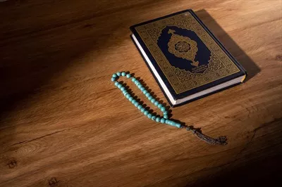 عکس مفهوم اسلامی قرآن کریم با خط عربی و تسبیح در کنار آن