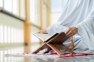 عکس مفهوم اسلامی: قرآن کریم با خط عربی و تسبیح در کنار آن