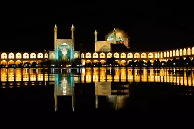 عکس ورود به مسجد جامع اصفهان در شب، با باغی زیبا در پیش زمینه
