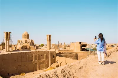عکس منظره زیبا از بام کاشان با بادگیرها و گردشگران در روزهای گرم تابستان