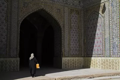عکس زنی که به سایه ورودی مسجدی در کاشان ایران وارد می شود