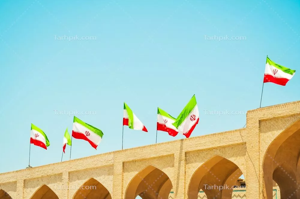 عکس پرچم های ایرانی در حال وزیدن بر بام یک ساختمان در روزی آفتابی