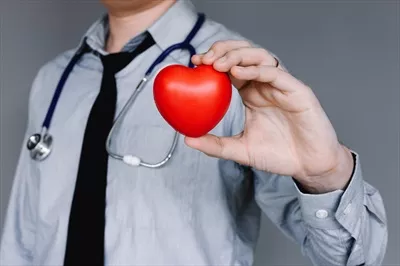 عکس پزشک با اعتماد به نفس در لباس غیررسمی و در دست داشتن قلب