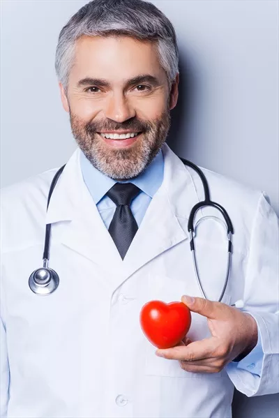 عکس دکتر قلب با اعتماد به نفس، در حال نگه داشتن اسباب بازی قلبی و لبخند زدن