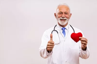 عکس پرتره ای از پزشک سالخورده با گوشی پزشکی در حال نشان دادن شکل قلب و علامت تایید