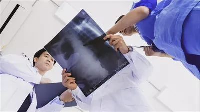عکس پزشک و دستیاران پزشکی در حال بررسی نتایج تشخیصی بر روی فیلم اشعه ایکس