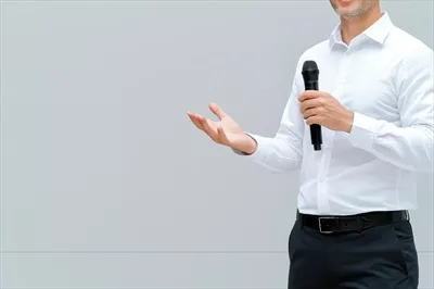 عکس سخنران تجاری در حال ارائه در یک محیط شرکتی با حرکات دست