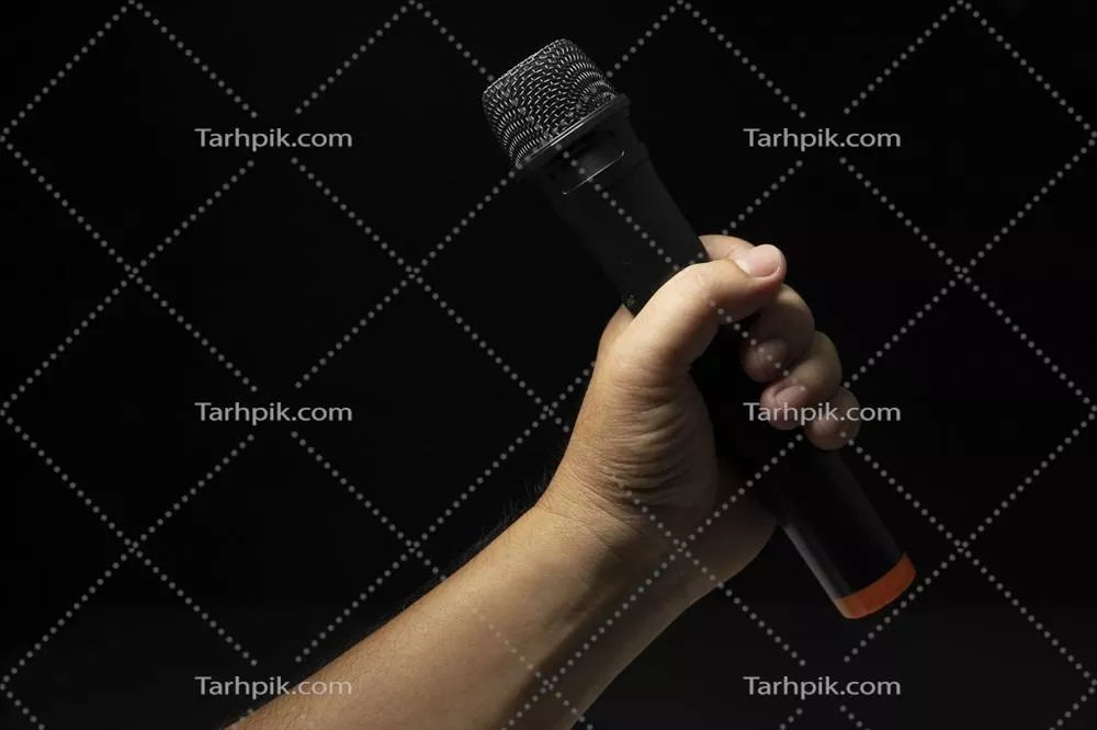 عکس میکروفون سیاه در دستان خواننده مرد بر روی صحنه مدرن با پس زمینه سیاه