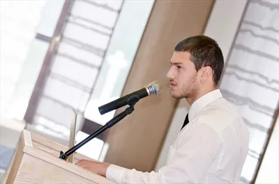 عکس مرد جوانی که در کنفرانس به ارائه مطالب می پردازد و مخاطبان را جذب می کند