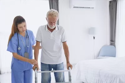 عکس فیزیوتراپیست و پرستار در حال حمایت از بیمار سالخورده برای بهبود حرکتی