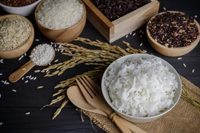 عکس برنج بخارپز با برنج ارگانیک و دانه برنج در یک میز چوبی
