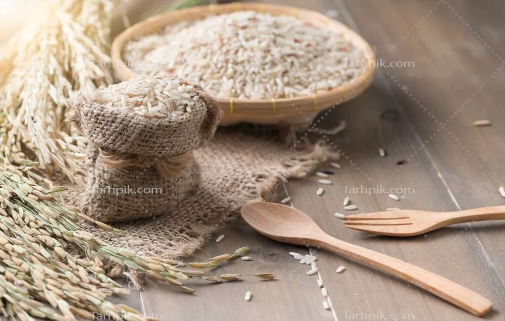 عکس برنج قهوه ای یاسمنی در سبد بامبو بر روی پس زمینه چوبی تیره