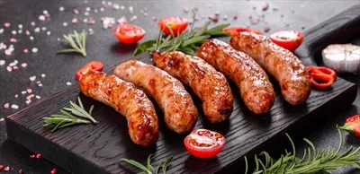 عکس سوسیس کبابی خوشمزه با سبزیجات و ادویه های معطر در پس زمینه سیاه