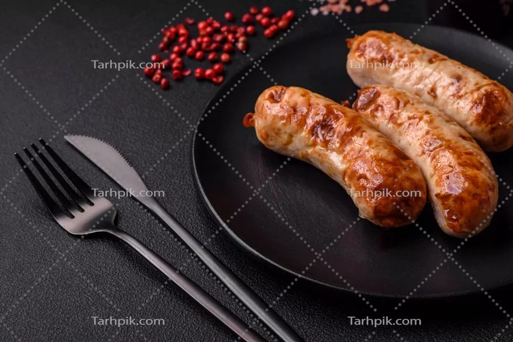 عکس سوسیس های کبابی خوشمزه و آبدار با ادویه و سبزیجات روی بشقاب سرامیکی