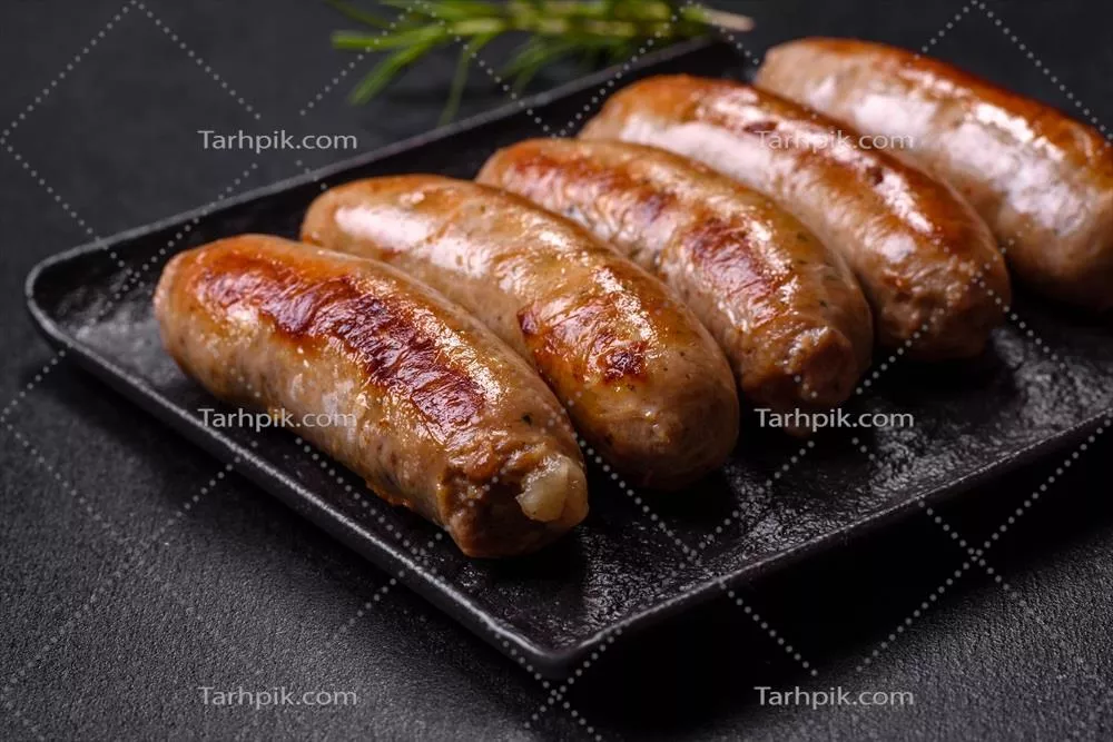 عکس سوسیس های کبابی خوشمزه با ادویه و گیاهان بر روی بشقاب سنگی مشکی