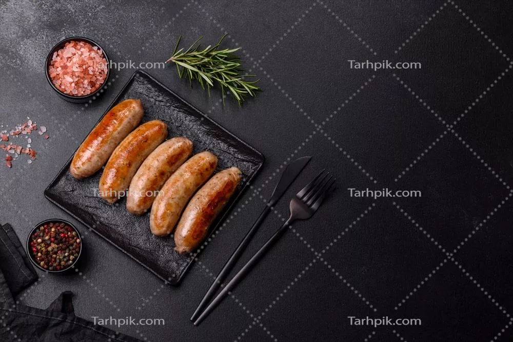 عکس سوسیس های کبابی خوشمزه با ادویه جات و گیاهان معطر روی بشقاب سنگی مشکی