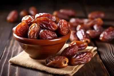 عکس خرماهای خشک شده بر روی میز چوبی با پس زمینه زیبا و طبیعی