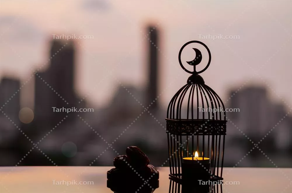 عکس چراغی با نماد ماه در بالای آن و بشقابی از خرما در افق صبحگاهی