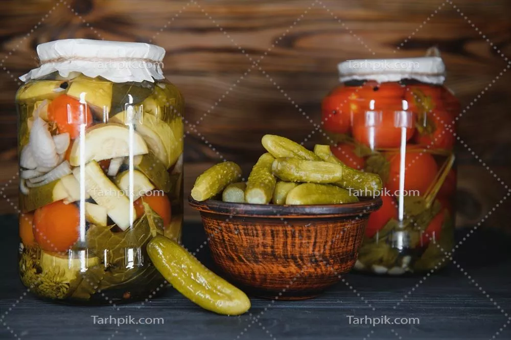 عکس شیشه های سبزیجات ترشی شده بر روی پس زمینه چوبی روستایی