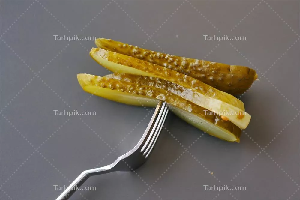 عکس نمای نزدیک از یک خیارشور روی بشقاب همراه با گوجه فرنگی ها