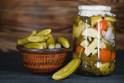 عکس ترکیب خیارشور و خیار تازه در کاسه ای چوبی بر روی میز روستایی