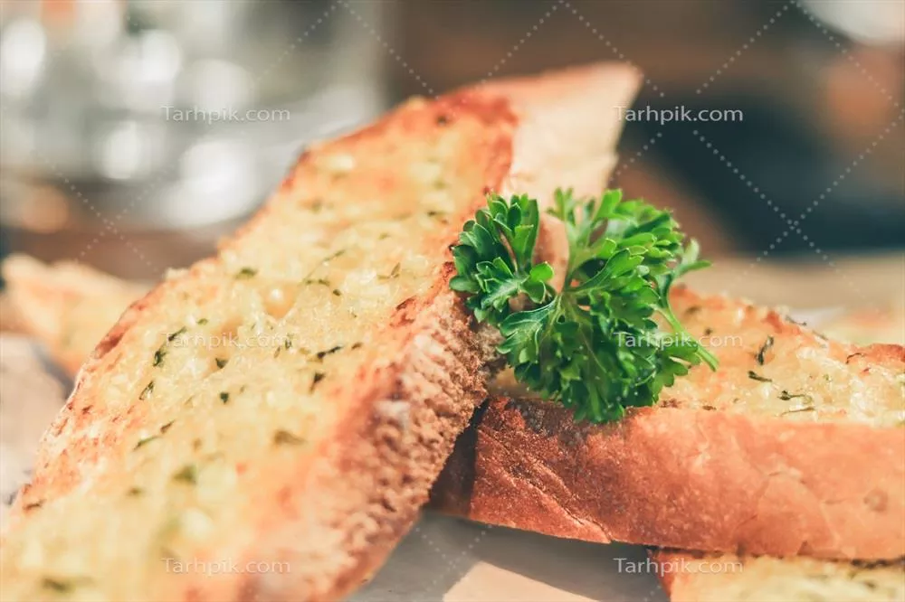 عکس تصویری نزدیک از نان سیر تازه پخته شده بر روی بشقاب چوبی