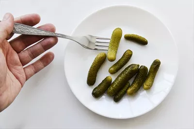 عکس ترکیب خوشمزه خیارشور سبز روی یک بشقاب سفید با چنگال