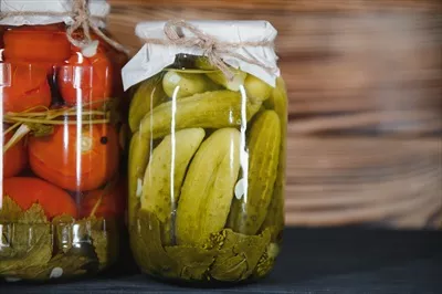 عکس شیشه های سبزیجات ترشی شده بر روی پس زمینه چوبی روستایی