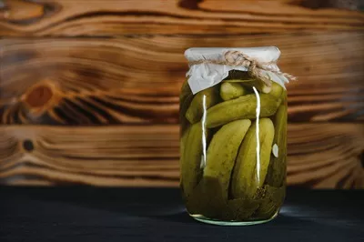عکس ترکیب خیارشور و خیار تازه در کاسه ای چوبی بر روی میز روستایی