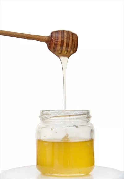 عکس عسل طبیعی و ارگانیک در حال چکیدن از قاشق عسل به داخل شیشه