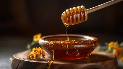 عکس عسل طبیعی و غلیظ در کاسه چوبی با قاشق چوبی و گل های زیبا