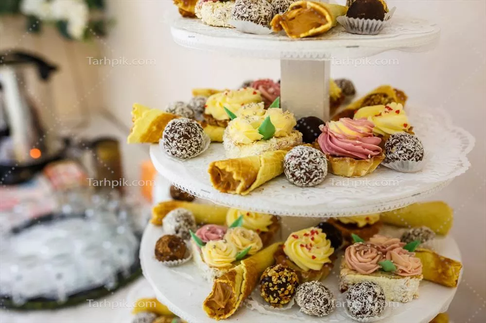 عکس نمایی زیبا از میز دسرهای جشن عروسی با تنوعی از شیرینی ها و تزئینات خاص
