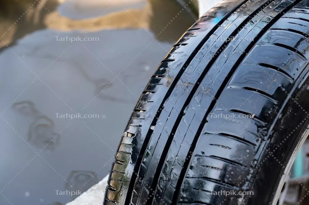 عکس نمای نزدیک از لاستیک خیس و آسیب دیده با یک سوراخ کوچک ناشی از میخ
