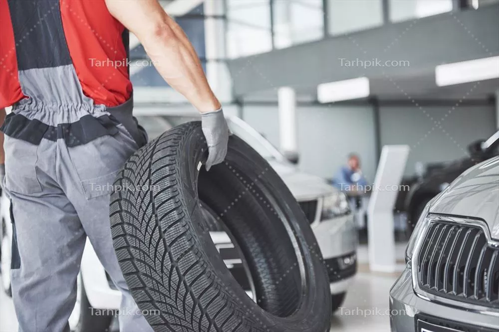 عکس مکانیک در حال تعویض لاستیک خودرو در تعمیرگاه تخصصی