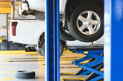 عکس خودروی پیکاپ در حال تعمیر بر روی بالابر در مرکز خدمات اتومبیل