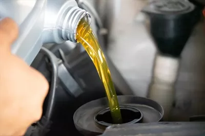 عکس ریختن روغن موتور تازه به داخل موتور خودرو در حین تعویض روغن