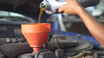 عکس مکانیک در حال تعویض روغن موتور خودرو با مایعات فنی جدید