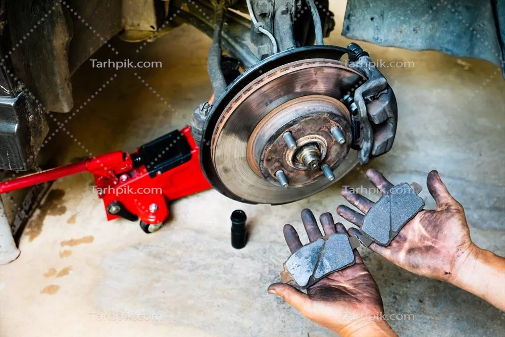 عکس بررسی آسیب دیدگی ترمز خودرو در دستان یک مکانیک با روغن موتور
