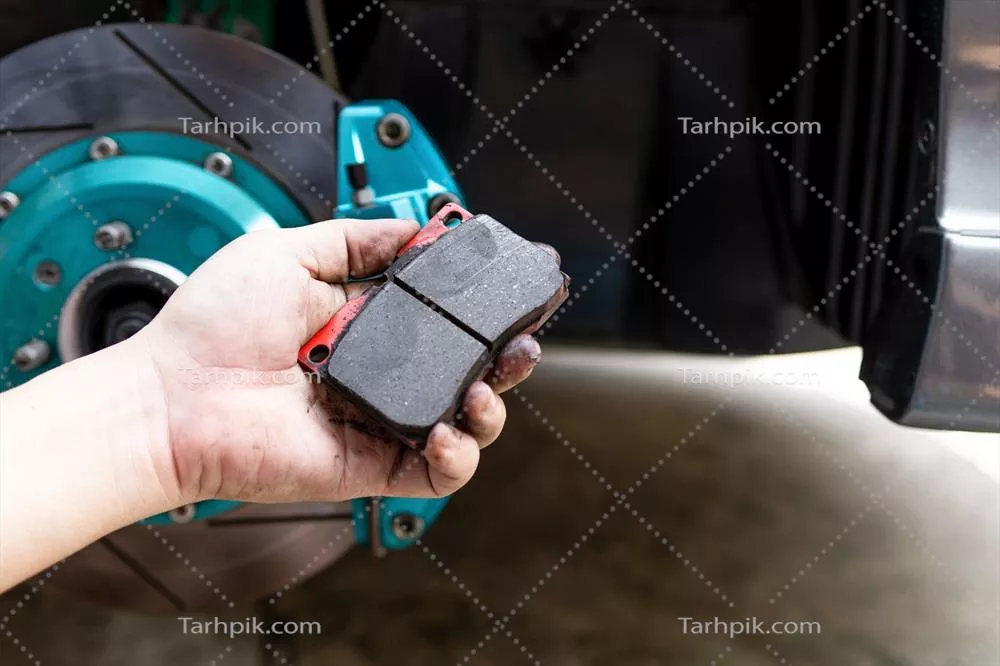 عکس بررسی ضخامت لنت ترمز قدیمی در دست یک مرد برای ارزیابی وضعیت آن