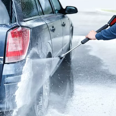 عکس کارگر شستشوی خودرو در حال تمیز کردن ماشین مشتری با دقت و مهارت